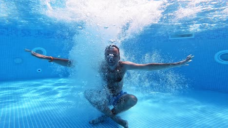 man jumps into clear water of a pool in yoga pose. underwater camera shooting a video of a man jumping into water. male shows gesture yes with thumbs underwater.