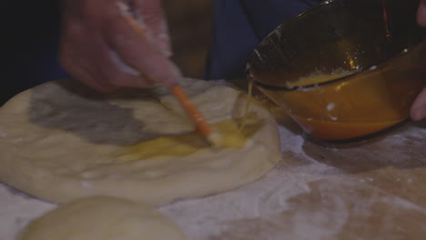 close up shot of a cook brushing traditional meskhetian bread with egg wash