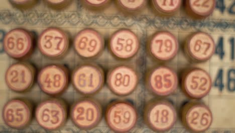 cinematic close-up smooth zoom in shot of a bingo wooden barrels, woody figures, on a old numbers textured background, vintage board game, professional lighting, slow motion 120 fps