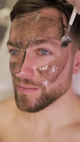 man getting charcoal facial mask applied