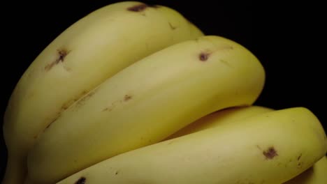 tilt up shot of banana bunch on black background, closeup