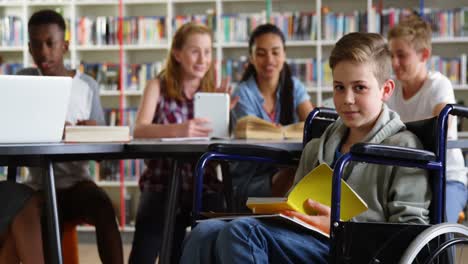 portrait of happy schoolboy reading book on wheelchair 4k