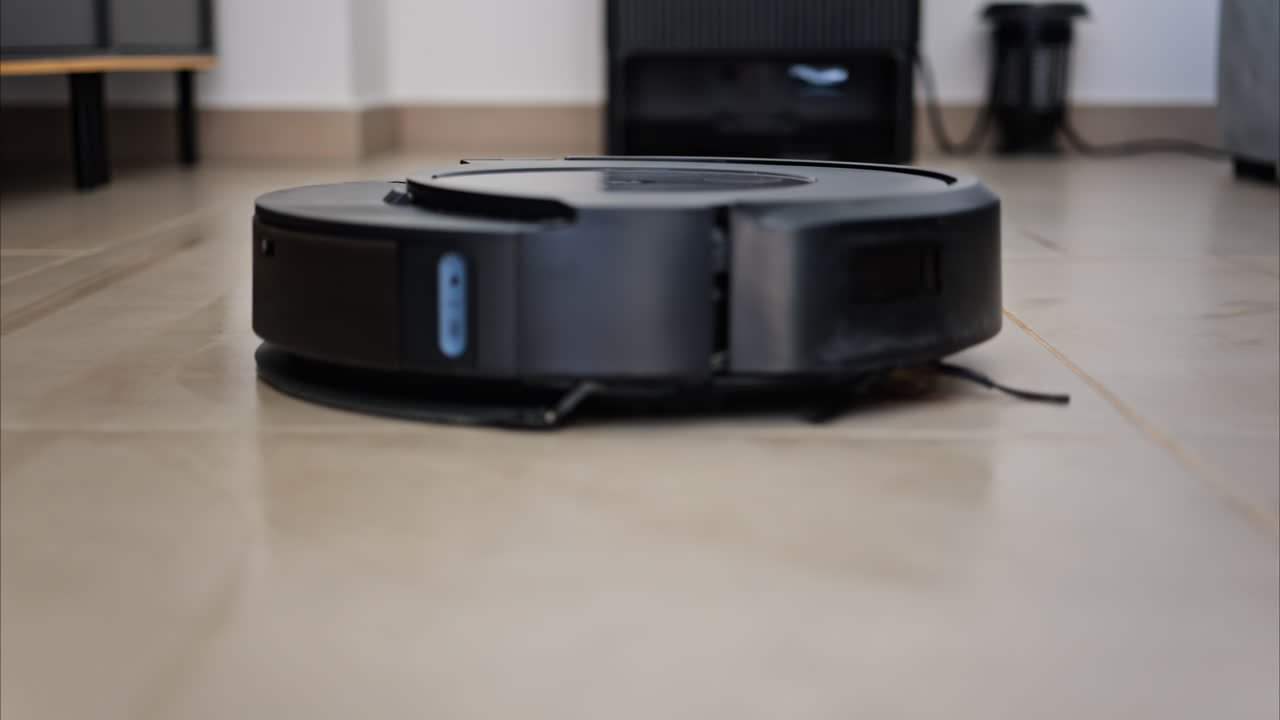 Close up of a small, black robot vacuum cleaning the house