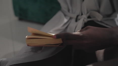 close-up of man's hand turning pages of book while sitting in peaceful bedroom. soft light highlights his fingers as he reads, creating a tranquil atmosphere for quiet reading and reflection