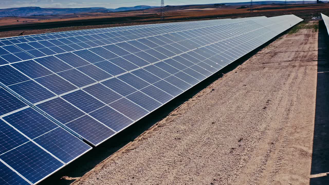 un disparo de un dron capturando una vista expansiva de una granja solar llena de numerosos paneles solares que se extienden en la distancia
