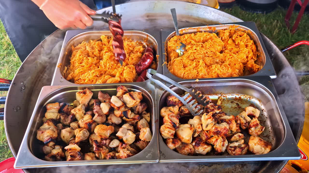 Steaming trays of grilled meat and sauerkraut on large skillet at food market