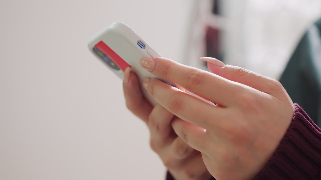 Persona leyendo en el teléfono, hojeando lentamente artículos en el dispositivo, persona concentrada interactuando con contenido durante la mañana, persona desplazándose atentamente por las noticias en un smartphone a la luz natural