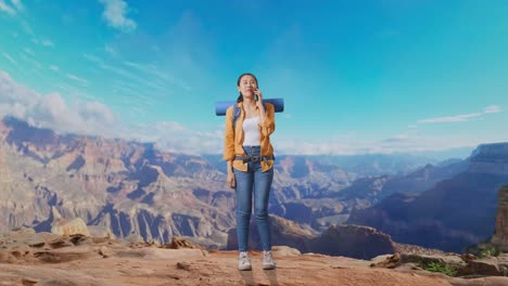 full body of asian female hiker with mountaineering backpack smiling and talking on smartphone while traveling at the top of mountain