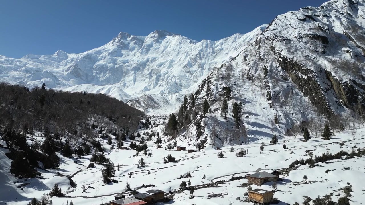 Ripresa aerea con drone di terreni alpini innevati e cime aspre vicino al campo base di Fairy Meadows nella Valle di Hunza, Pakistan. Paesaggio invernale selvaggio d'alta quota
