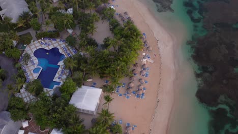 drone view of ocean,boat,parasols and sandy caribbean beach at sunrise,grand bahia principe beach at samana peninsula,dominican republic