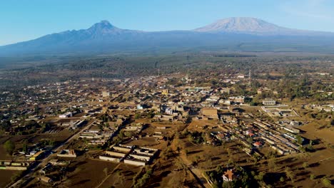 Sunrise--Kenya-landscape-with-a-village,-Kilimanjaro-and-Amboseli-national-park---tracking,-drone-aerial-view