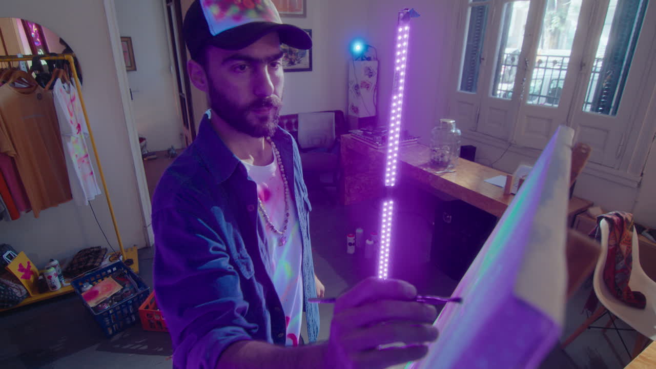 Male Painter Painting Picture on Canvas with Luminous Paint under UV Light