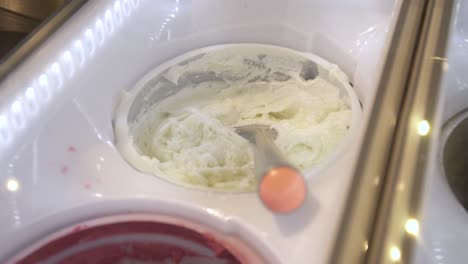helado de vainilla con cuchara en el congelador de exhibición de la cremería, de mano