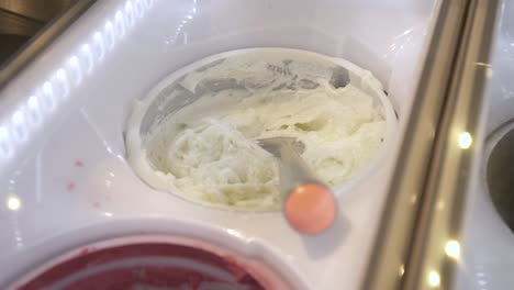 vanilla ice cream with scoop in creamery display freezer, handheld