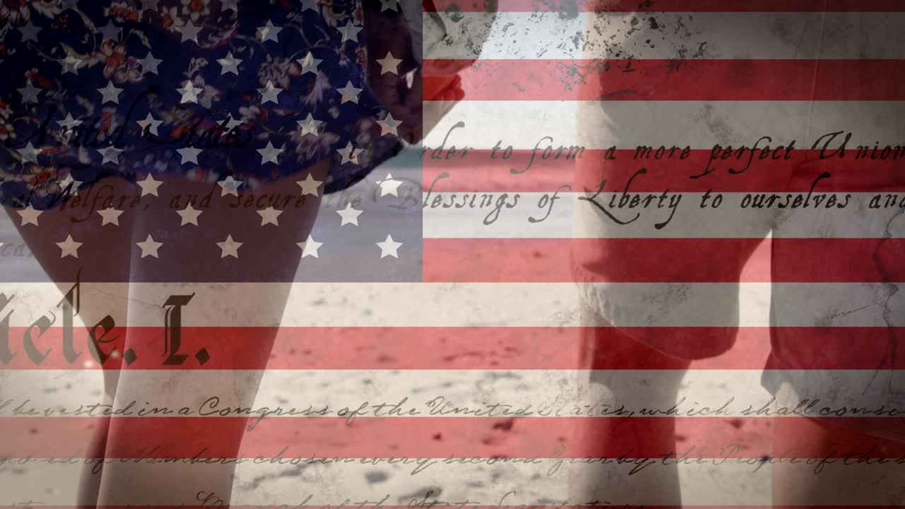 Animation of American flag waving and constitution text over mixed race couple by seaside