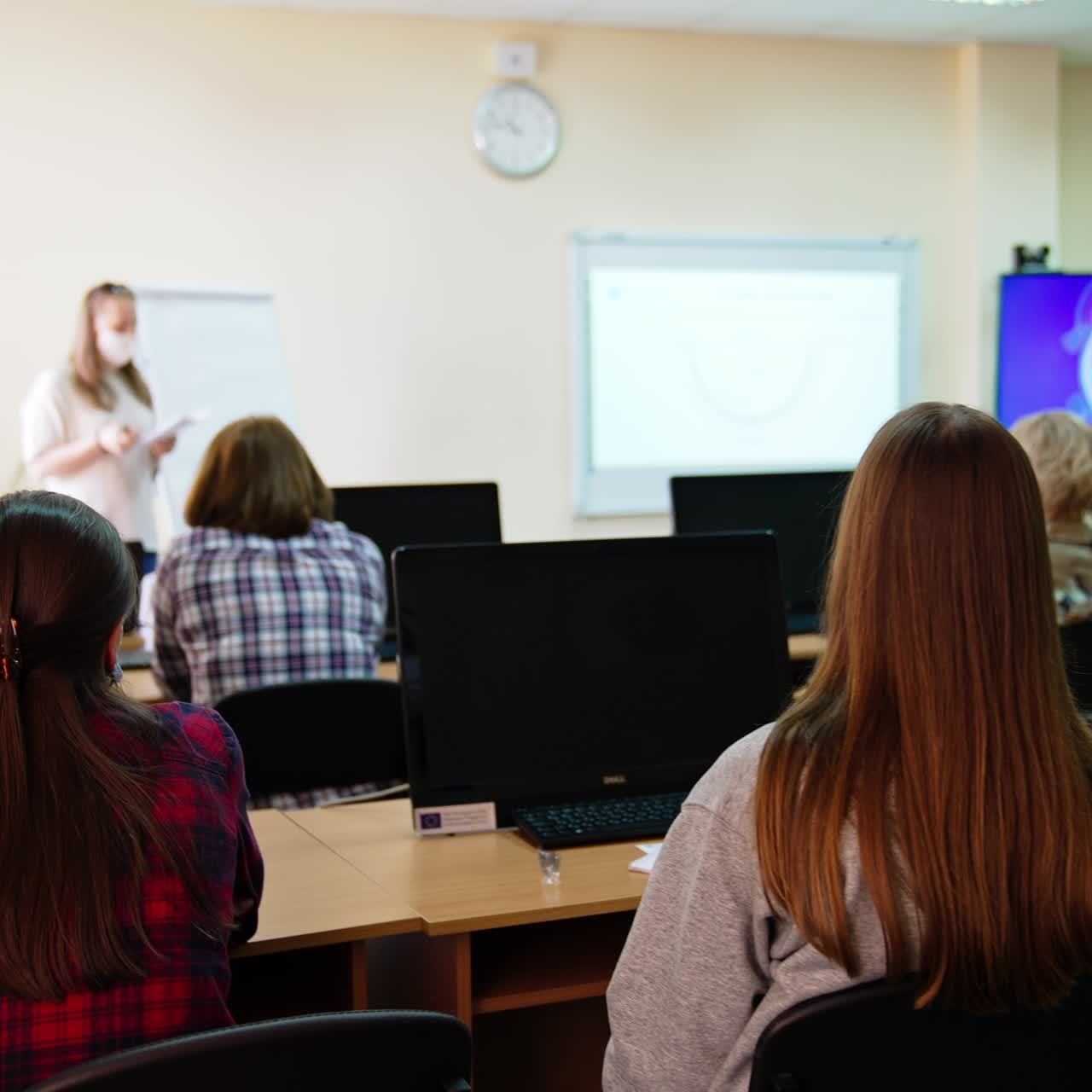 Female auditory attending lecture on ophthalmology. Students sit at the desks in front of computer screens