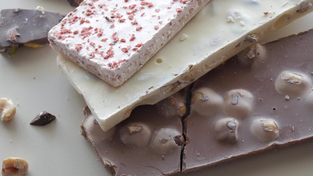 Top view of an assortment of dark and white chocolates with crushed nuts, offering a visually pleasing gourmet presentation.
