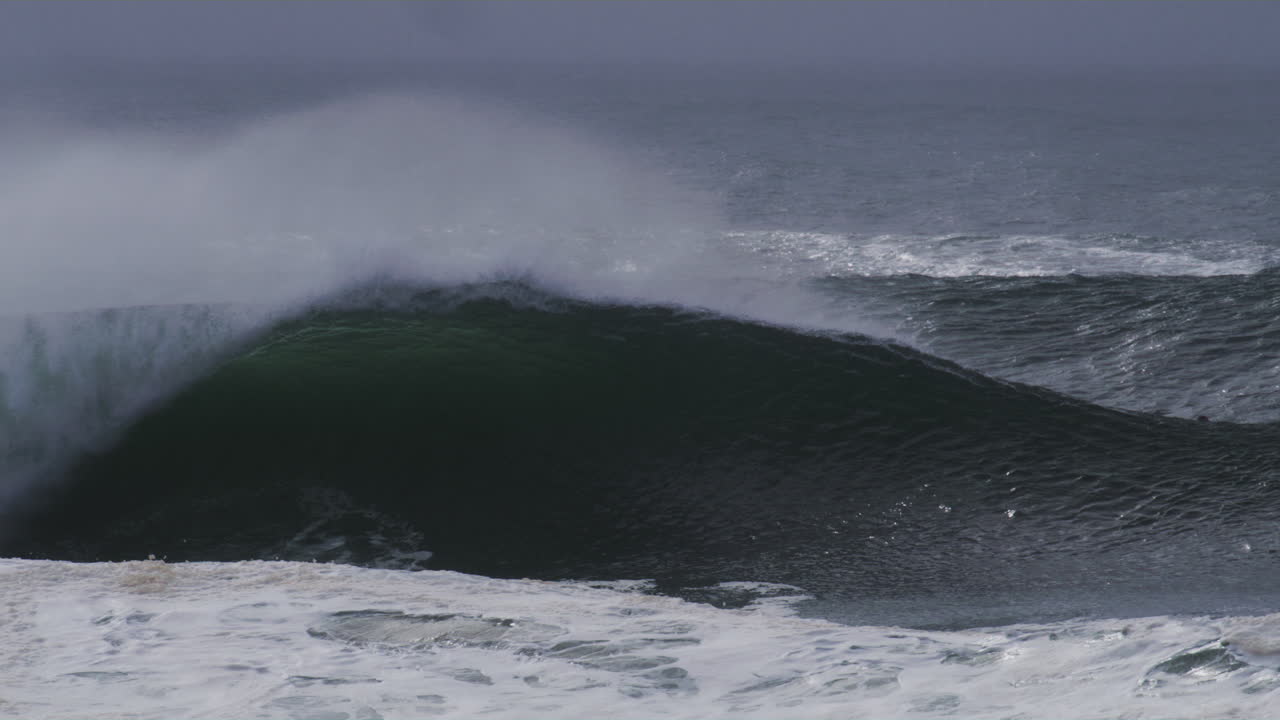 Huge wave forms a perfect barrel, mist drifting off as it crashes forward