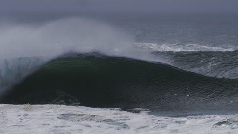 huge wave forms a perfect barrel, mist drifting off as it crashes forward