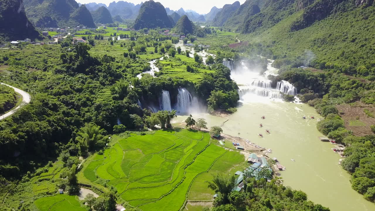 Ban Gioc Waterfalls on a sunny day with lush green fields around
