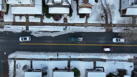 top down aerial of cars driving on snowy streets in winter