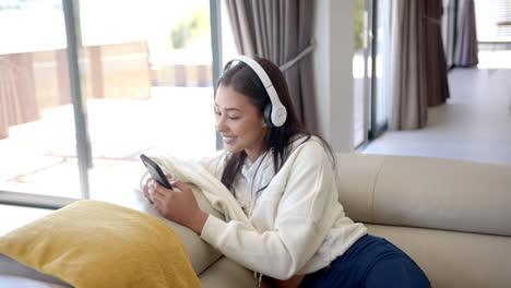 listening to music, woman relaxing on couch with headphones and smartphone