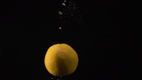 un clip en cámara lenta de una naranja que cae en cámara lenta en el agua