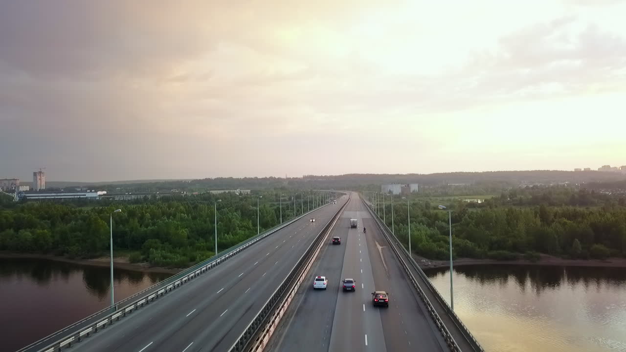 Aerial view of a bridge with cars over a river surrounded by trees