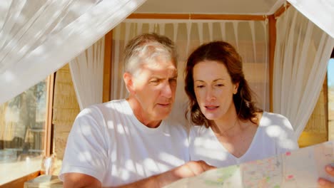 couple looking at map while relaxing on canopy bed 4k