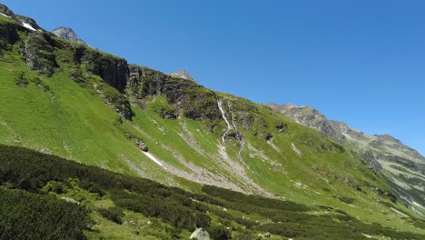 Flying-through-a-beautiful-green-valley-with-waterfalls-in-the-Austrian-Alps,-Uttendorf-Weissee