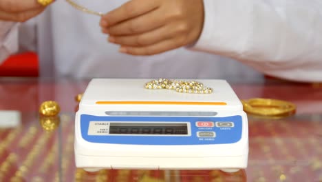 digital scales for weighing gold rings and necklaces with hand in store