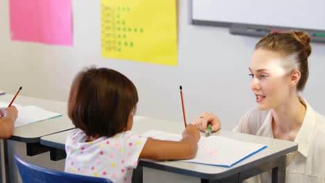 Teacher-helping-kids-with-their-homework-in-classroom