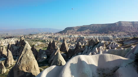 epic cinematic revealing drone shot of a lone man standing among the fairy chimneys and looking at the mountains in cappadocia, turkey