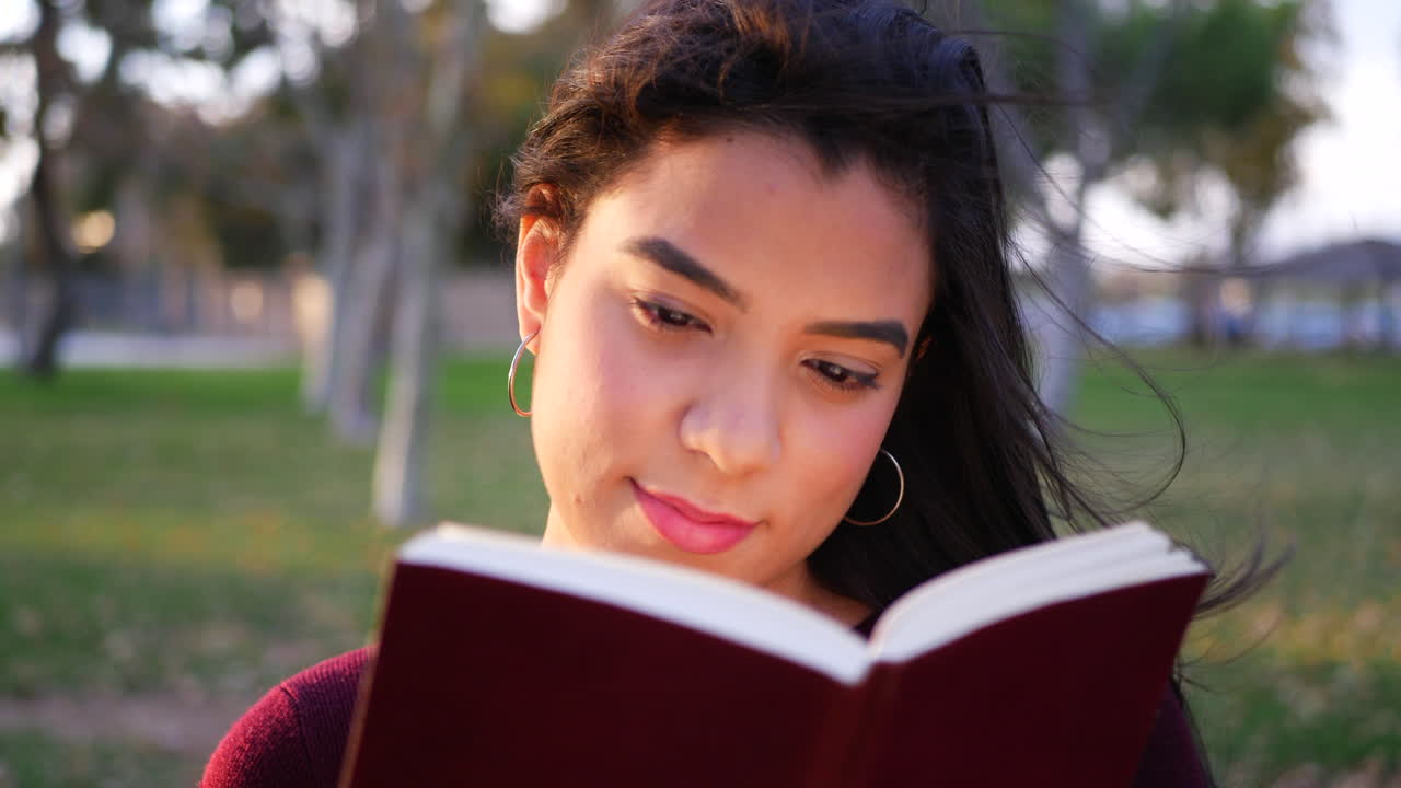 Primo piano su una studentessa universitaria che legge e studia un libro di testo prima della lezione nel campus. SLOW MOTION