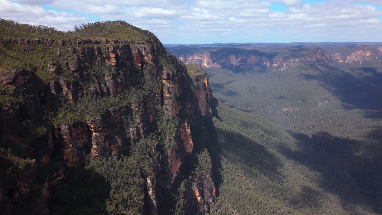Drone sweeps over rugged rocky cliffs framed by eucalyptus forest, golden light illuminating scene, Blue Mountains NSW Australia