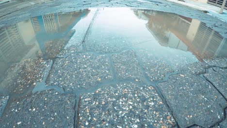 slight drizzle falls on puddle in street