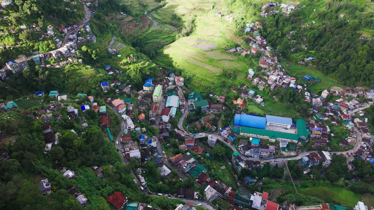 Drone ascende sobre Banaue, revelando casas na encosta e terraços de arroz