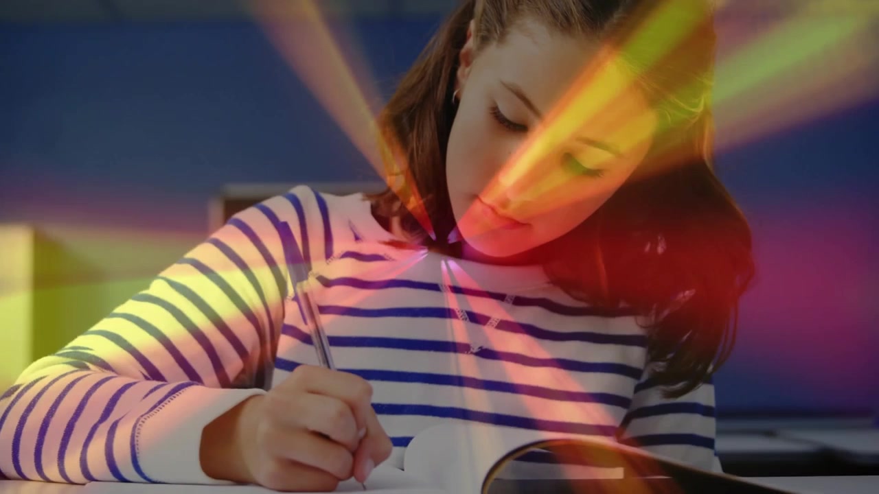 Female student picking pencil and writing on notebook on desk in class with light streaks sweeping