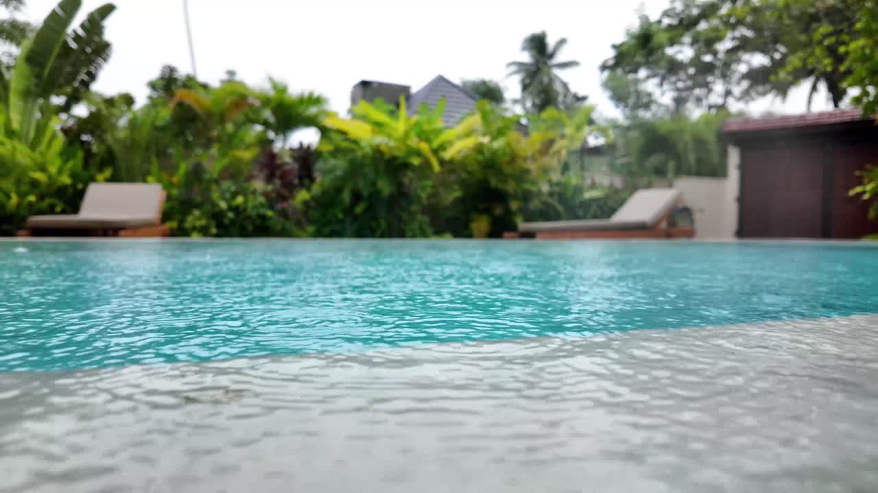Rain over water surface swimming pool bright blue color, texture heavy rainfall downpour
