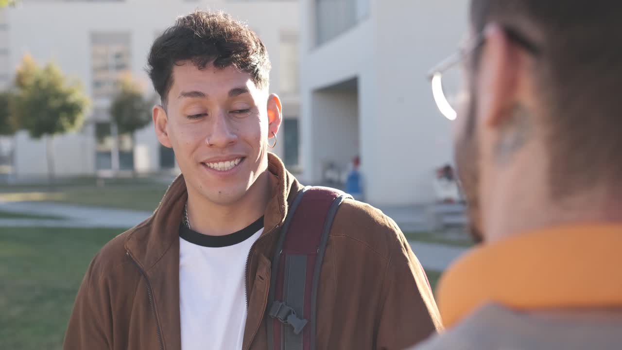 Focus on a hispanic modern man talking with a friend outside the university