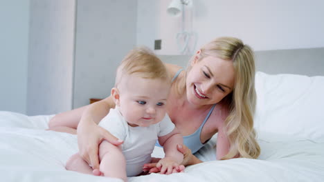 mother playing on bed at home with baby son