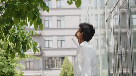 Primer-Plano-Medio-Del-Exitoso-Hombre-De-Negocios-Observando-El-árbol-Fuera-Del-Edificio