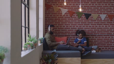 jóvenes estudiantes de negocios afroamericanos estudian juntos trabajando en proyectos creativos intercambiando ideas escuchando música usando auriculares en el lugar de trabajo moderno de la oficina