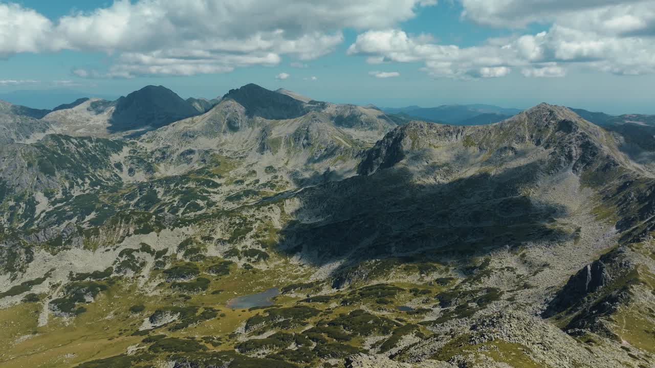 Aerial view showing beautiful alpine landscape with tall mountain ranges and glacial lakes, sunny day with blue sky