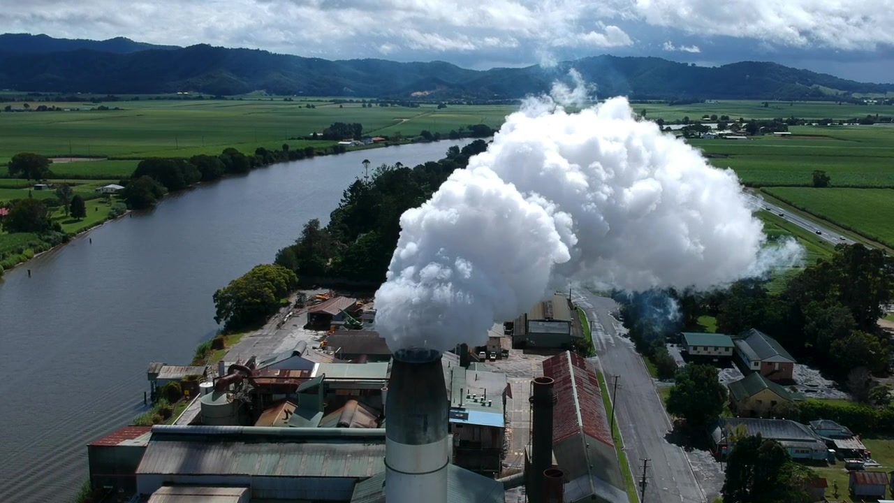 Fumo che esce da una ciminiera industriale accanto a un fiume