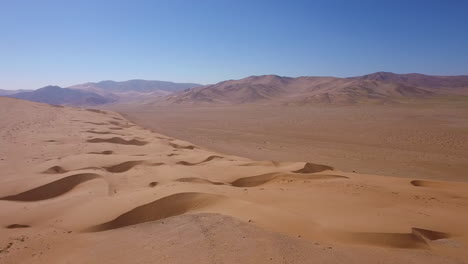 aerial landscape shot of the golden dry sand and mountainous horizon of the atacama desert, bright sunlight