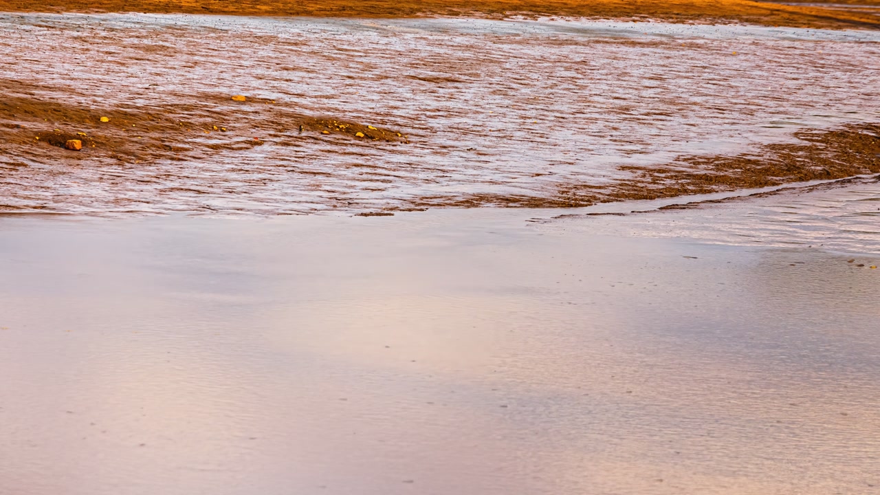 Muddy shallow water and exposed lakebed textures showing drought and low water conditions