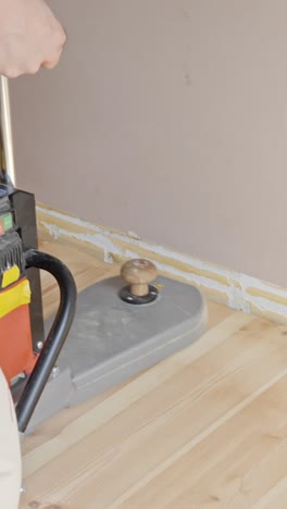 man sanding wooden floor edges with a vertical edge sander indoors