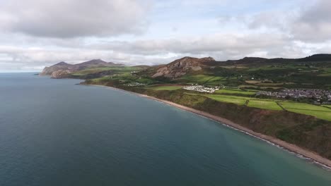 vista aérea de la larga media luna de arena de la playa de nefyn en la península de illyn mirando hacia el fuerte de la edad de hierro y las montañas del eifl