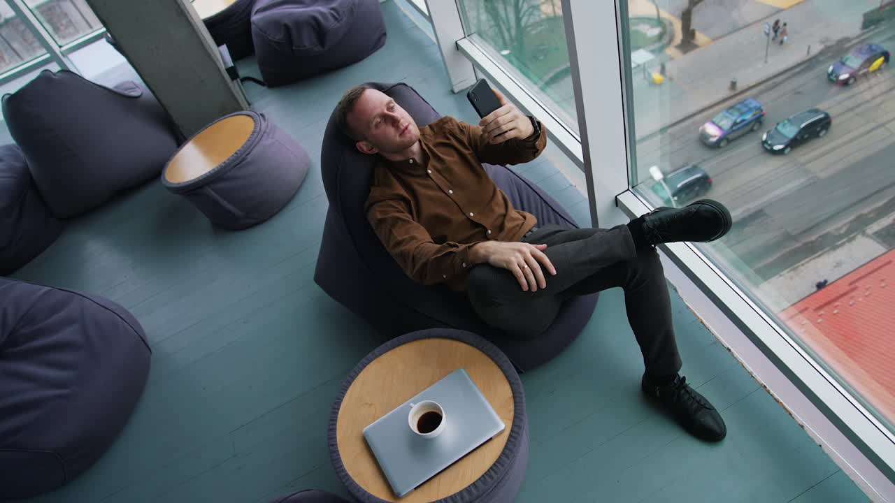 Happy young businessman using smartphone in office